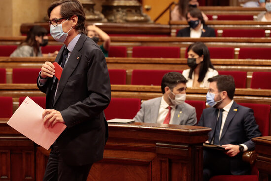 Socialist Salvador Illa, left, getting up to address the Parliament as vice president Jordi Puigneró and president Pere Aragonès chat in the background (by Job Vermeulen)